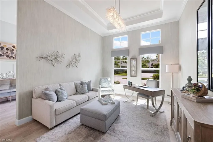 Living room featuring a high ceiling, a raised ceiling, and an inviting chandelier