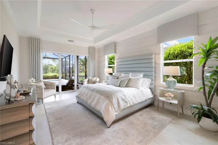 Bedroom with light tile floors, ceiling fan, a raised ceiling, and access to outside