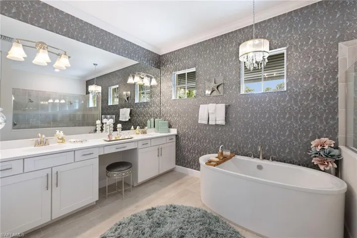 Bathroom featuring a bath to relax in, ornamental molding, double sink, and large vanity