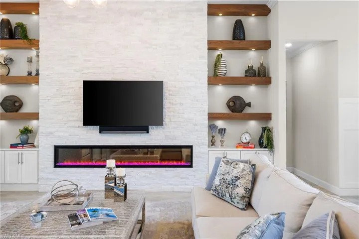 Tiled living room featuring a stone fireplace and built in features