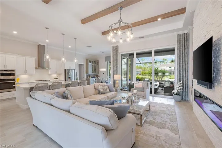 Living room with beam ceiling, light tile floors, and a chandelier