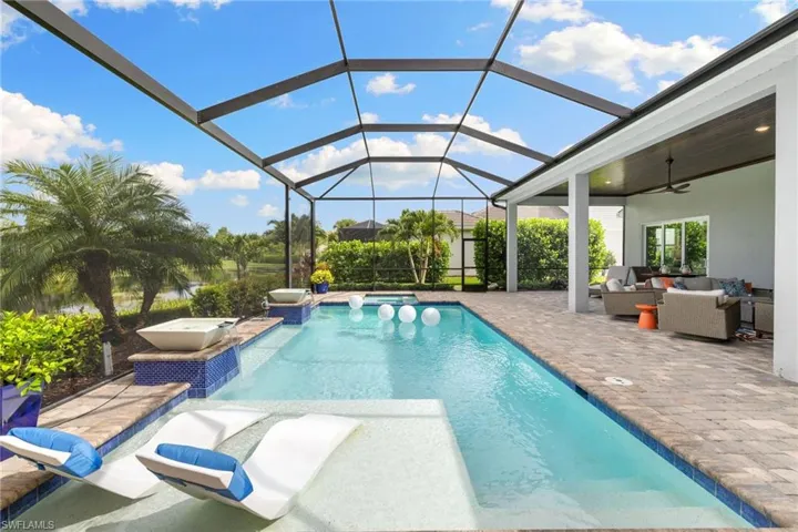 View of swimming pool with a patio, an outdoor living space, pool water feature, glass enclosure, and ceiling fan