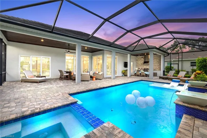 Pool at dusk featuring ceiling fan, outdoor lounge area, glass enclosure, and a patio area