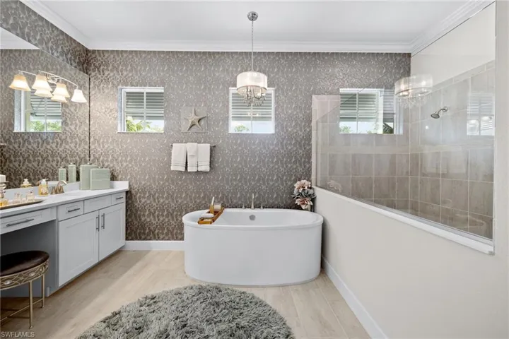 Bathroom with ornamental molding, vanity, and an inviting chandelier