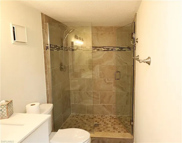 Bathroom with a shower stall, vanity, and a textured ceiling
