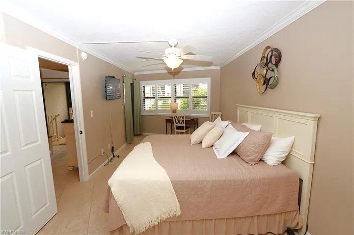 Bedroom with crown molding, light tile patterned floors, and ceiling fan