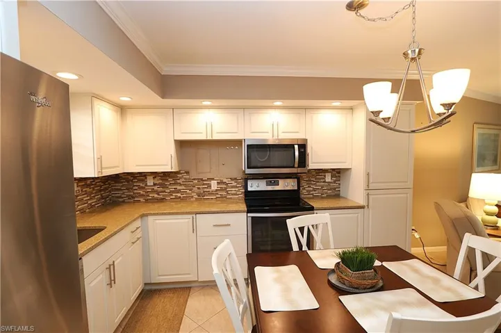 Kitchen with crown molding, stainless steel appliances, recessed lighting, tasteful backsplash, and white cabinets