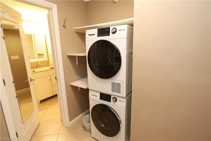Laundry room with light tile patterned floors and stacked washer / dryer