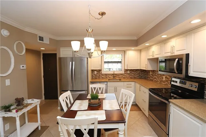 Kitchen featuring appliances with stainless steel finishes, ornamental molding, recessed lighting, decorative light fixtures, and white cabinets