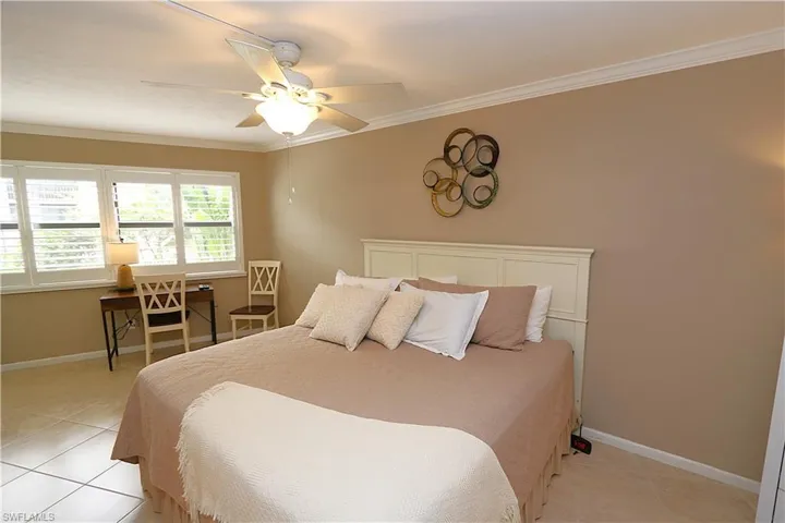 Bedroom with crown molding, light tile patterned floors, and ceiling fan