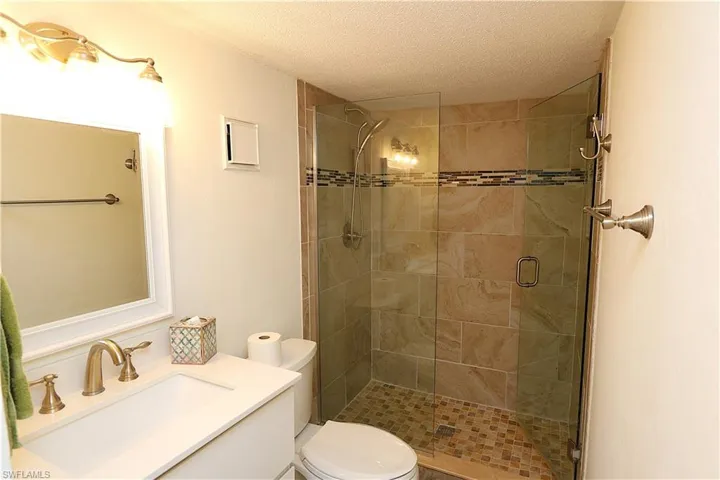 Full bath with vanity, a stall shower, and a textured ceiling