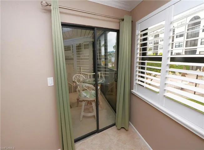 Doorway featuring crown molding and tile patterned floors