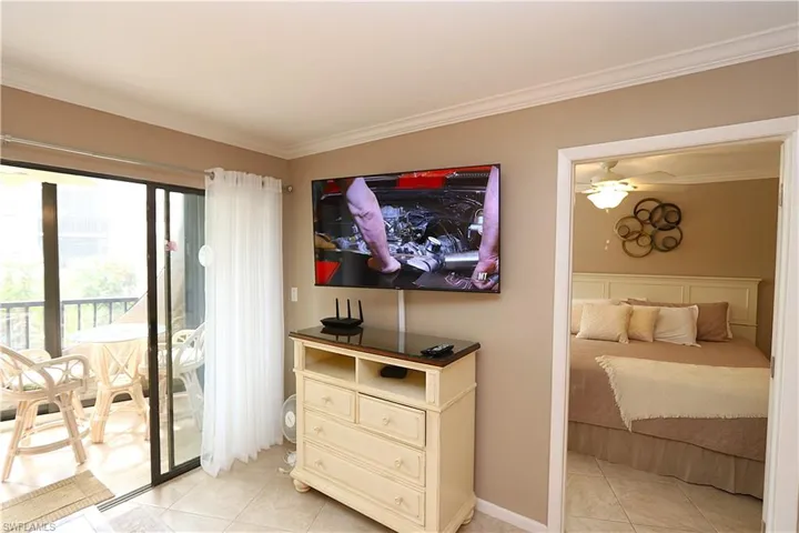 Bedroom with crown molding, access to exterior, and light tile patterned flooring