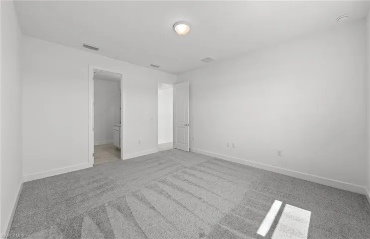 Unfurnished bedroom with a spacious closet, ensuite bathroom, and carpet floors