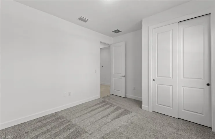 Unfurnished bedroom featuring a closet and light colored carpet