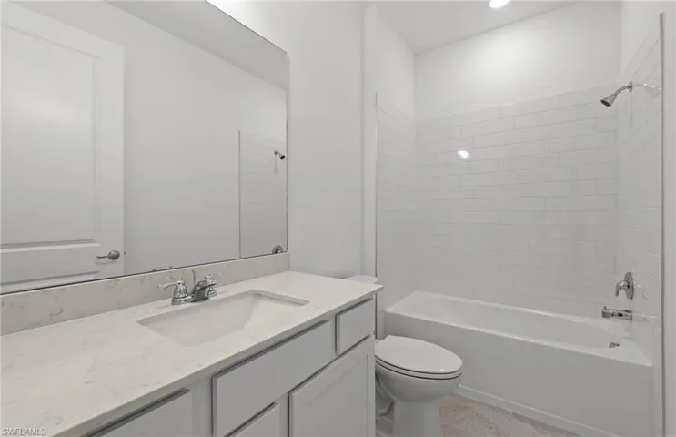 Full bathroom featuring tiled shower / bath, toilet, and vanity