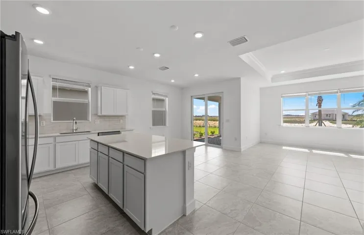 Kitchen with a center island, stainless steel fridge, sink, tasteful backsplash, and light tile floors
