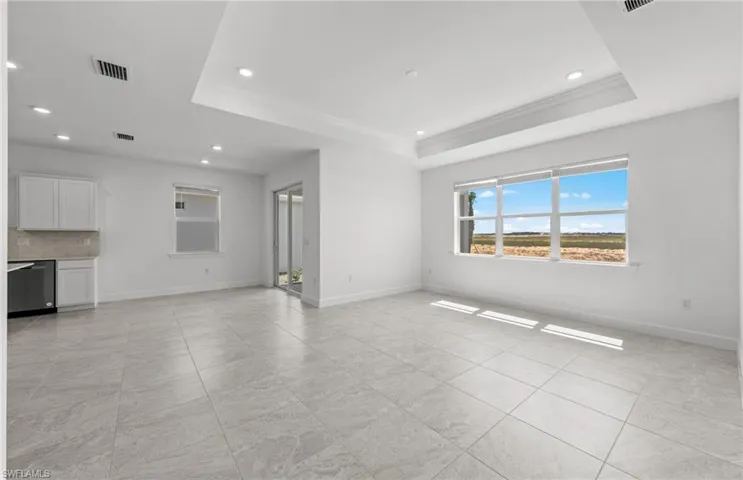 Unfurnished living room featuring a tray ceiling and light tile flooring