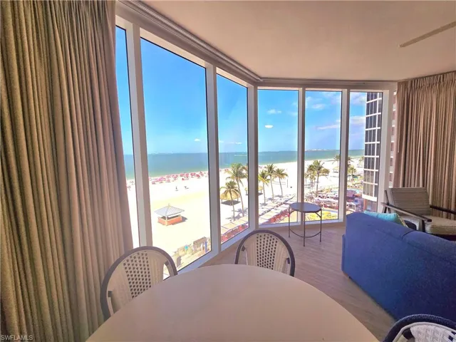 Wall of glass with a beach view, wood finished vinyl floors, floor to ceiling windows, and a water view