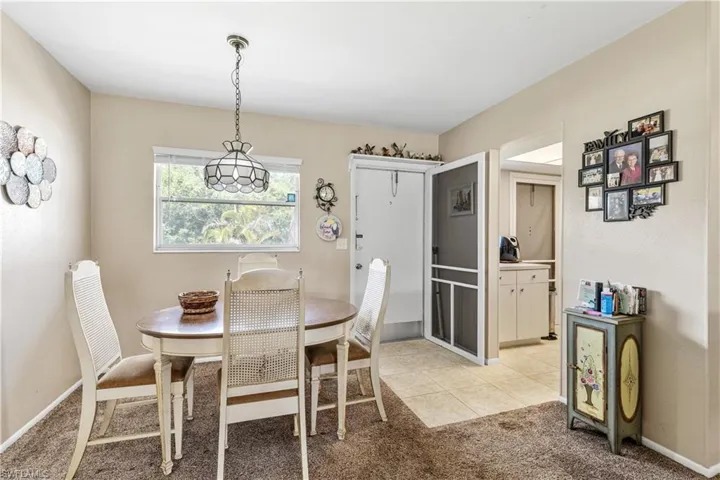 Dining room with light colored carpet, baseboards, and light tile patterned flooring