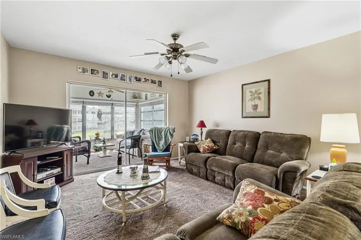 Carpeted living area with ceiling fan