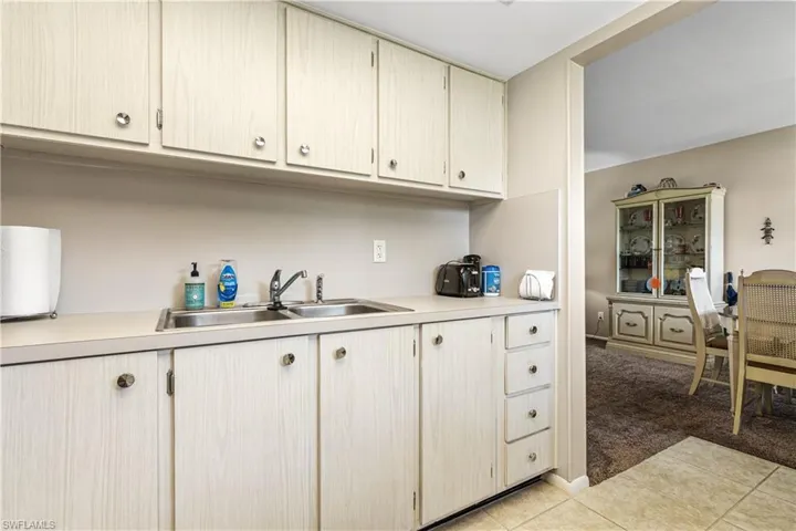Kitchen featuring a sink, light countertops, light carpet, and light tile patterned floors