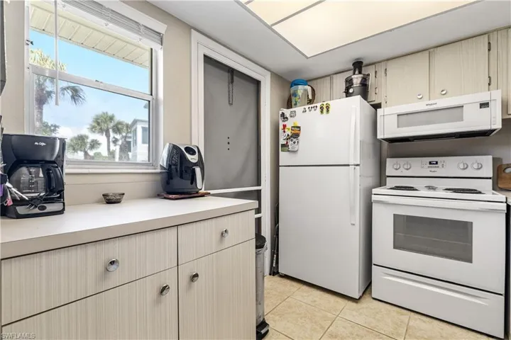 Kitchen featuring white appliances, light countertops, and light tile patterned floors