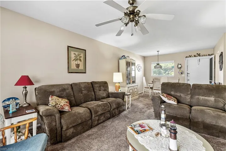 Carpeted living room featuring a ceiling fan and baseboards