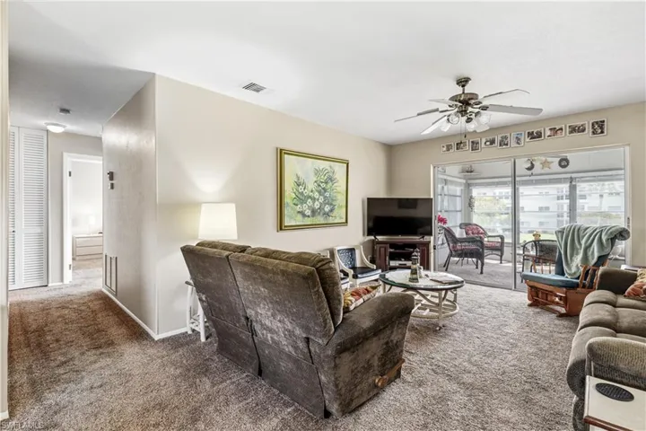 Living room with carpet flooring, a ceiling fan, and baseboards