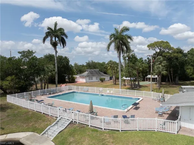 Community pool with a patio and view of wooded area