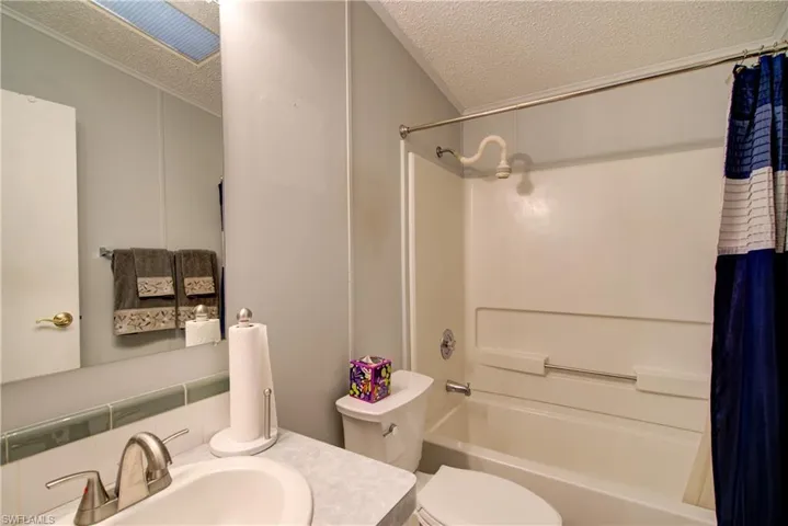 Bathroom with shower / tub combo, a textured ceiling, and vanity