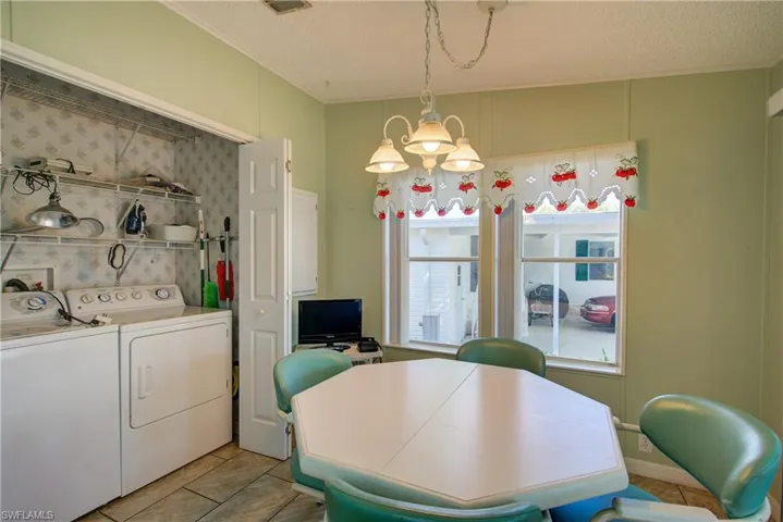 Dining room with light tile patterned flooring, a textured ceiling, crown molding, separate washer and dryer, and a chandelier