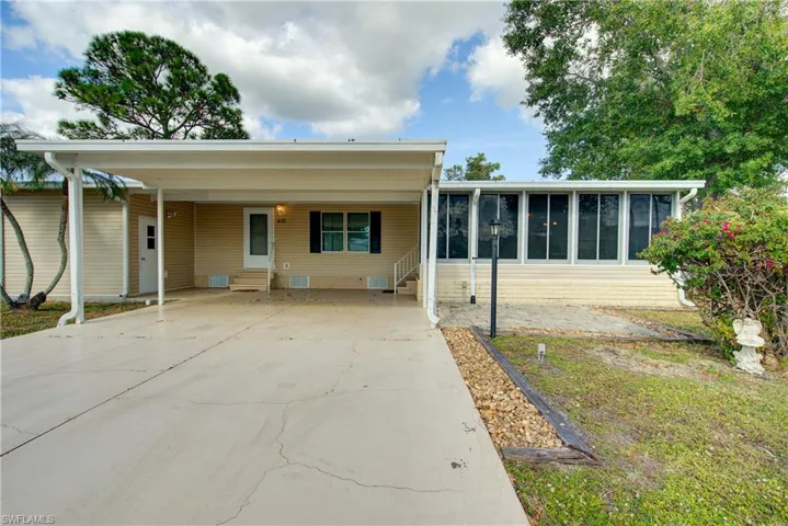 Ranch-style home featuring entry steps, a carport, driveway, a patio area, and a sunroom