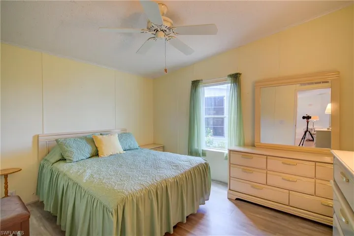 Bedroom featuring a decorative wall, light wood-style flooring, a textured ceiling, ceiling fan, and ornamental molding