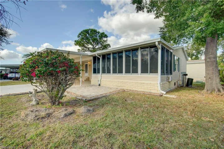 side of house with a sunroom, a lawn, and a patio area