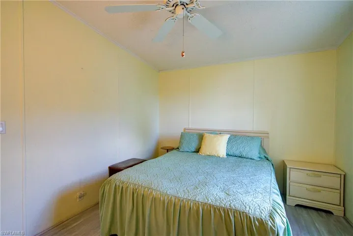 Bedroom featuring ceiling fan, crown molding, and wood finished floors