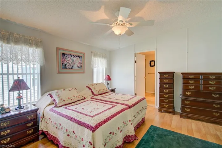 Bedroom with light wood-style floors, a textured ceiling, a ceiling fan, and lofted ceiling