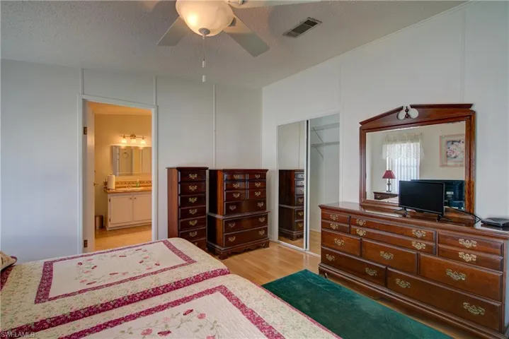 Bedroom with light wood-style flooring, ceiling fan, a textured ceiling, and a closet