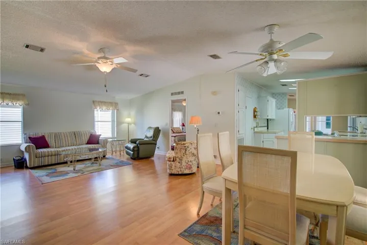 Dining area with a ceiling fan, wood finished floors, a textured ceiling, and vaulted ceiling