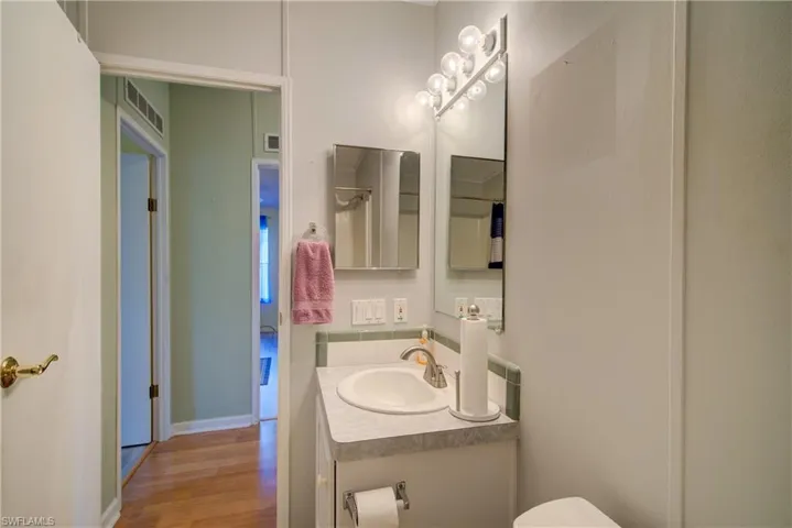 Half bathroom featuring vanity and wood finished floors