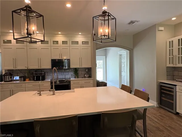 Kitchen featuring beverage cooler, a chandelier, appliances with stainless steel finishes, arched walkways, and recessed lighting