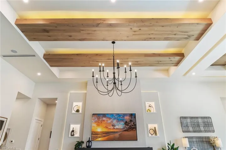 Detailed view of recessed lighting, a raised ceiling, a chandelier, and wood ceiling with exposed beams