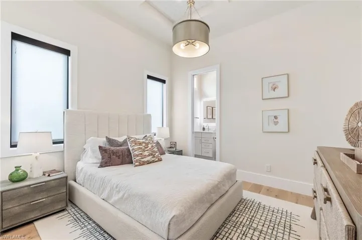 Bedroom with light wood-style floors, baseboards, and connected bathroom