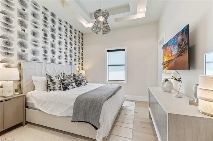 Bedroom featuring light wood-style floors, baseboards, and a raised ceiling