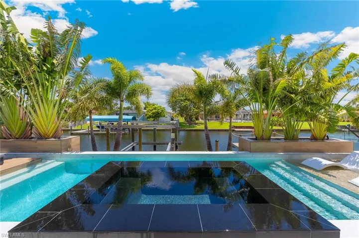 View of pool with a water view, a boat dock, and a pool with connected hot tub