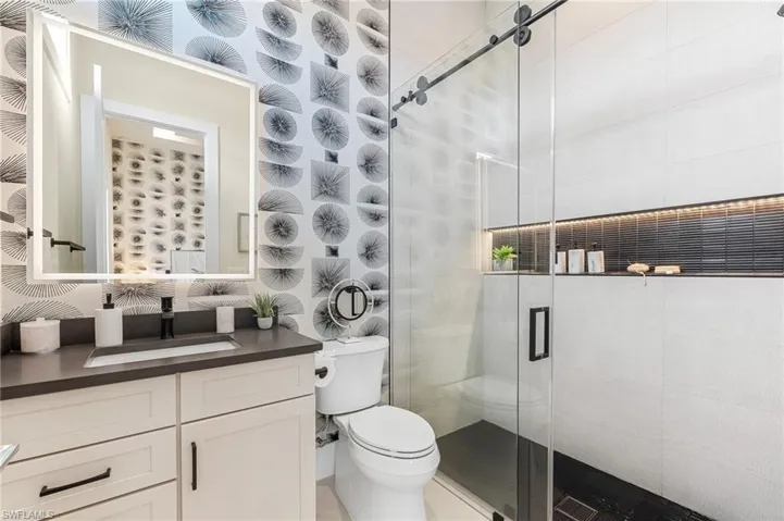 Bathroom with toilet, vanity, and a shower stall