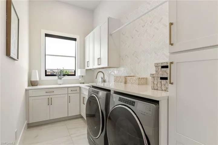 Washroom with separate washer and dryer, cabinet space, and light marble finish floors