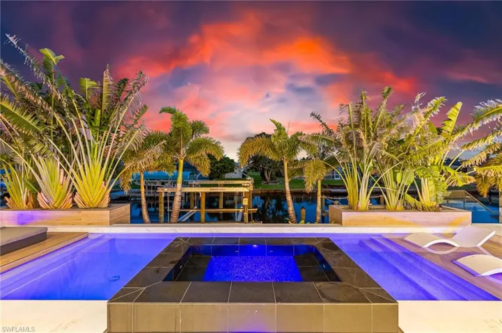 Pool at dusk with an in-ground hot tub and a water view