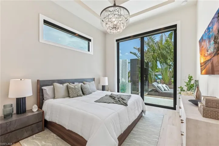 Bedroom with access to exterior, a chandelier, and light wood-style flooring