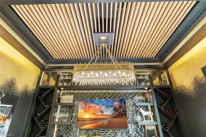 Wine area featuring a textured wall, ornamental molding, and a chandelier